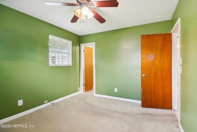 unfurnished bedroom with ceiling fan, light carpet, and a textured ceiling