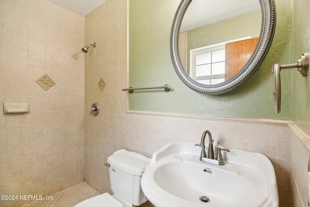 bathroom featuring toilet, sink, tile walls, and tiled shower