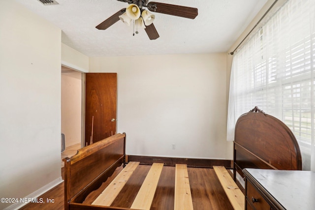 bedroom featuring a textured ceiling, dark hardwood / wood-style floors, and ceiling fan