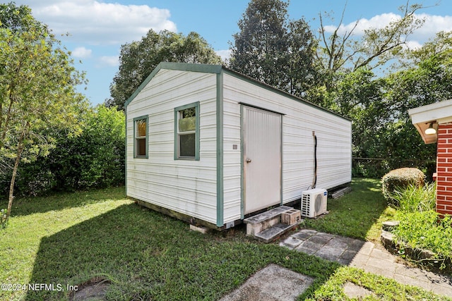 view of outdoor structure featuring ac unit and a lawn