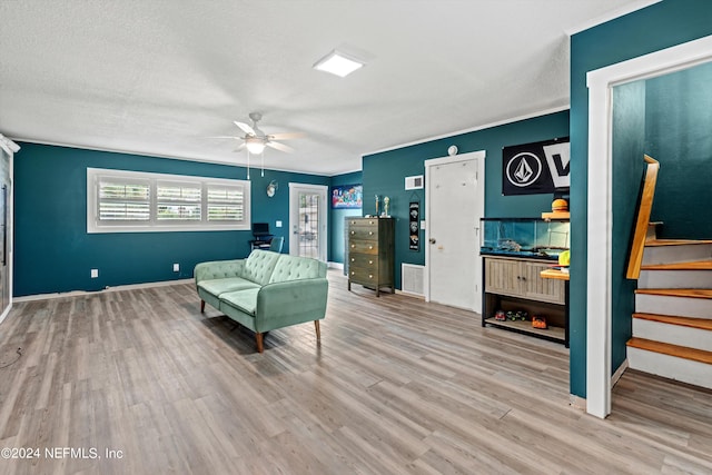 sitting room with light wood-type flooring, a textured ceiling, and ceiling fan