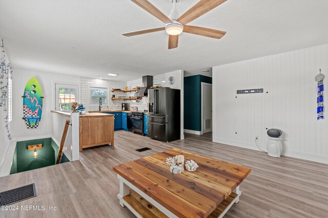 living room featuring light wood-type flooring, ceiling fan, sink, and a textured ceiling