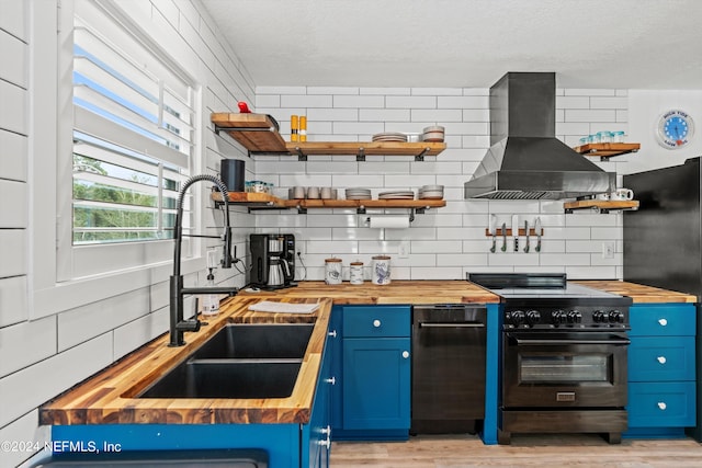 kitchen featuring butcher block countertops, black stove, and wall chimney exhaust hood