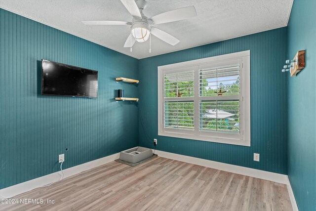 spare room with hardwood / wood-style floors, ceiling fan, and a textured ceiling