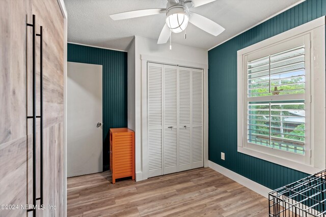 bedroom with a textured ceiling, hardwood / wood-style floors, ceiling fan, and a closet