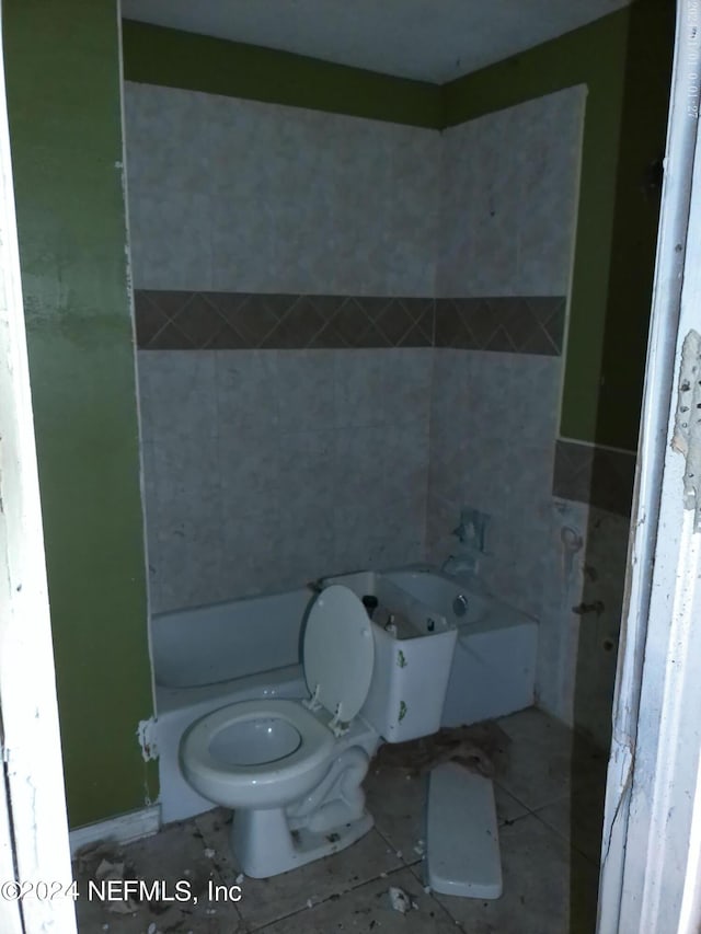 bathroom featuring a tub, toilet, and tile patterned floors