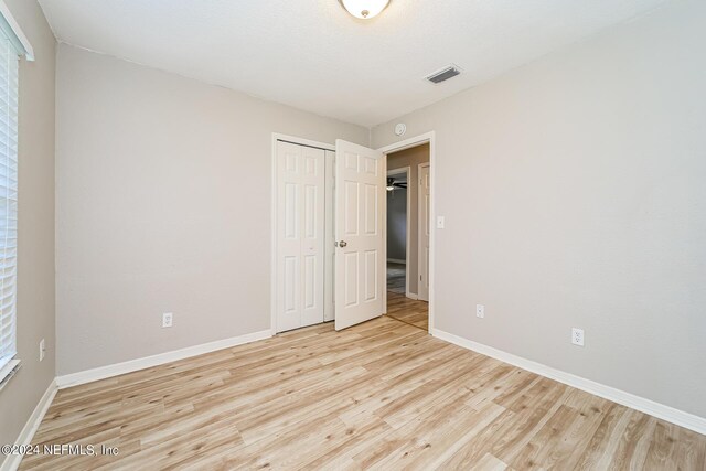 unfurnished bedroom featuring light wood-type flooring and a closet