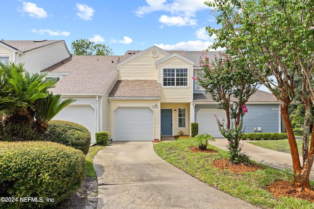 townhome / multi-family property featuring a garage, roof with shingles, and driveway