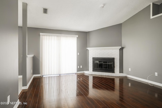 unfurnished living room featuring a fireplace, dark hardwood / wood-style floors, and a textured ceiling