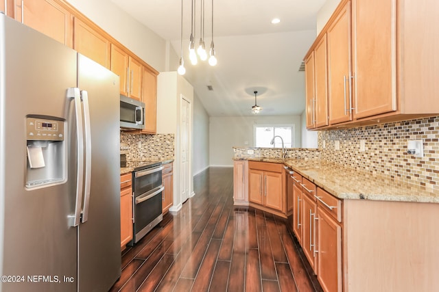 kitchen featuring hanging light fixtures, light stone countertops, stainless steel appliances, sink, and dark wood-type flooring