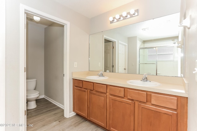 bathroom with an enclosed shower, toilet, hardwood / wood-style flooring, and vanity