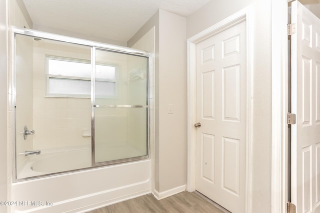 bathroom featuring shower / bath combination with glass door, a textured ceiling, and wood-type flooring