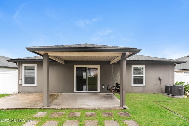 rear view of property featuring central AC unit, a patio area, and a lawn