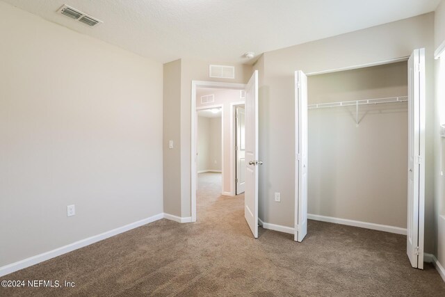 unfurnished bedroom featuring light colored carpet and a closet