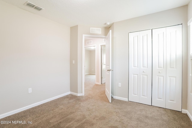 unfurnished bedroom featuring visible vents, light carpet, baseboards, and a closet