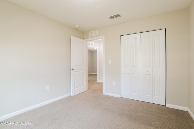 unfurnished bedroom featuring a closet and light carpet