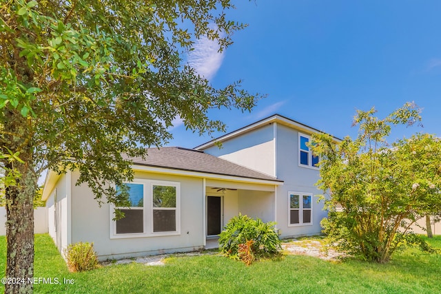 rear view of property featuring a yard and ceiling fan