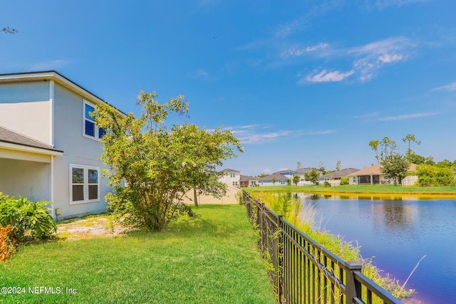 view of yard featuring fence, a water view, and a residential view