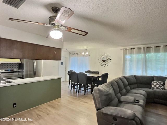 living room featuring a wealth of natural light, a textured ceiling, ceiling fan with notable chandelier, and light hardwood / wood-style floors