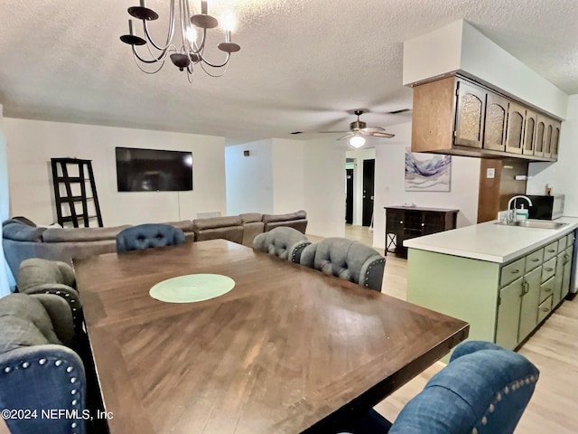 dining room with ceiling fan with notable chandelier, light hardwood / wood-style floors, a textured ceiling, and sink