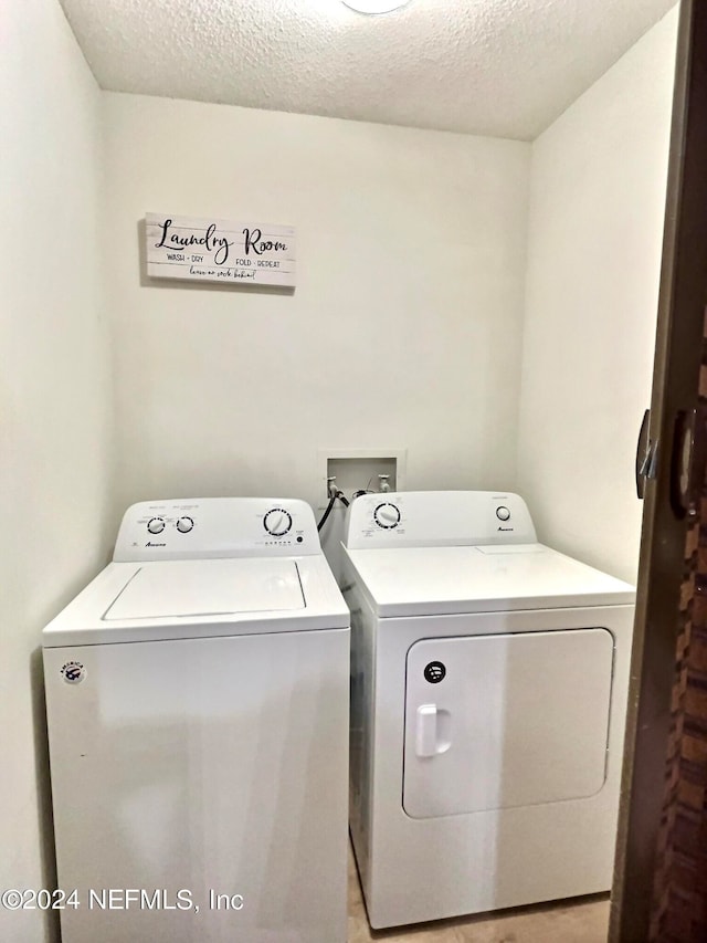 laundry room featuring a textured ceiling and washing machine and dryer