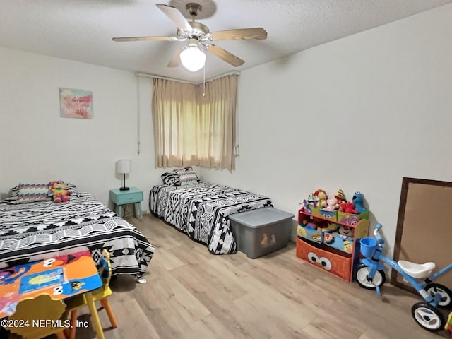 bedroom with a textured ceiling, ceiling fan, and light hardwood / wood-style floors