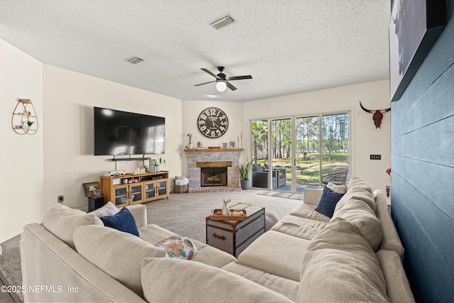 9042 Ford Rd, Bryceville, FL 32009 - carpeted living area featuring visible vents, a fireplace, a textured ceiling, and ceiling fan