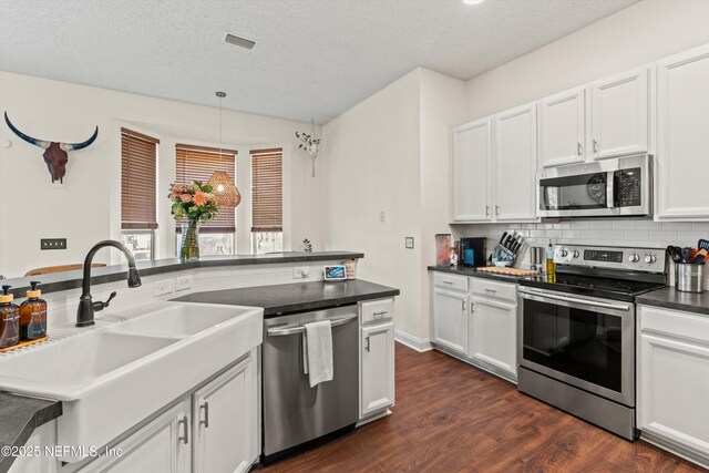 9042 Ford Rd, Bryceville, FL 32009 - kitchen with stainless steel appliances, visible vents, a sink, decorative backsplash, and dark wood-style flooring