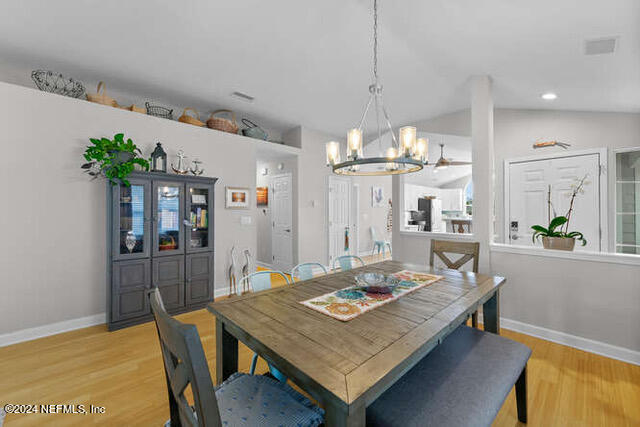 dining room featuring lofted ceiling, an inviting chandelier, and light wood-type flooring