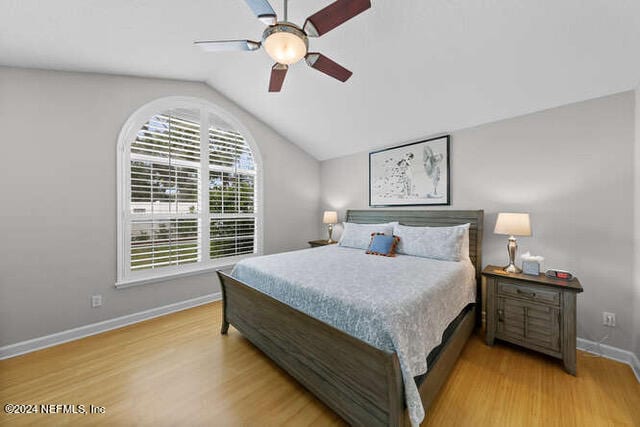 bedroom with ceiling fan, light hardwood / wood-style floors, and vaulted ceiling