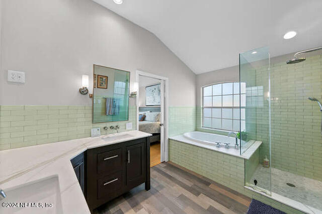 bathroom featuring vanity, vaulted ceiling, hardwood / wood-style flooring, and shower with separate bathtub