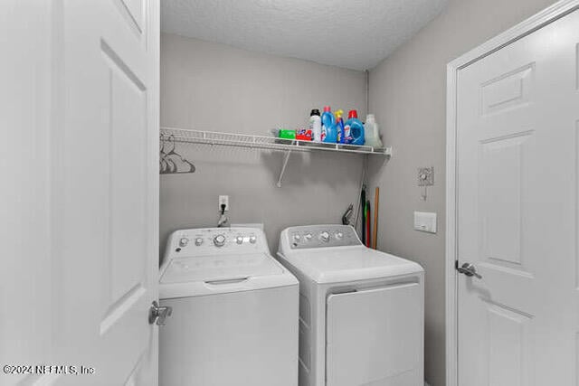 washroom featuring a textured ceiling and washing machine and dryer