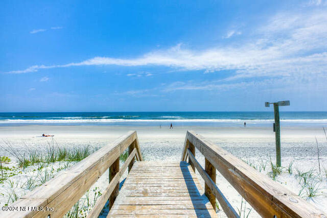 dock area with a water view and a beach view