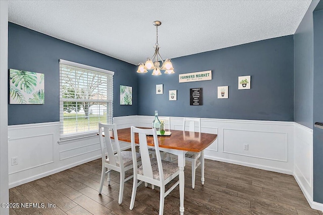 dining area featuring a textured ceiling, dark hardwood / wood-style flooring, and an inviting chandelier