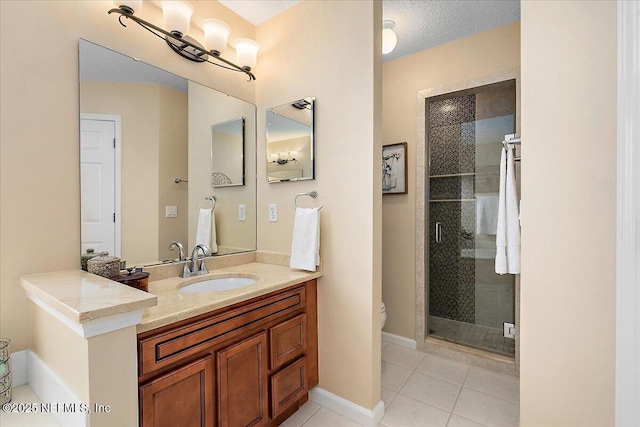 bathroom with a textured ceiling, vanity, tile patterned flooring, and a shower with shower door