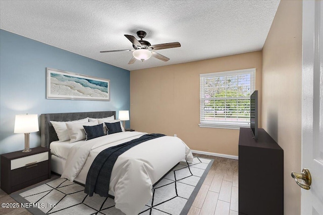 bedroom featuring light wood-type flooring, ceiling fan, and a textured ceiling