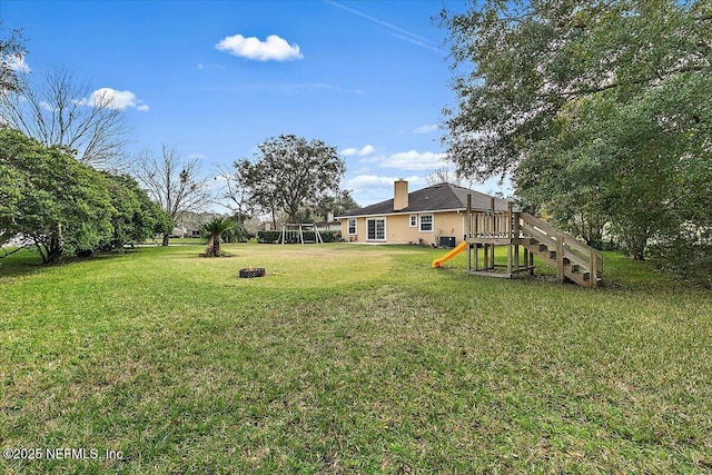 view of yard featuring central air condition unit, a fire pit, and a playground