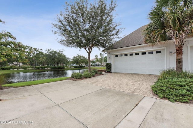 garage with decorative driveway and a water view