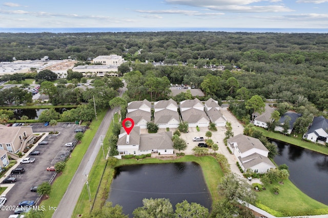 drone / aerial view with a residential view, a wooded view, and a water view