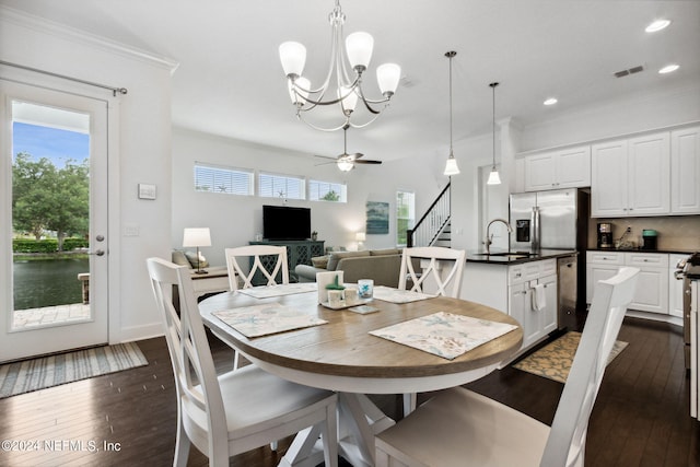 dining room with dark wood-type flooring, a healthy amount of sunlight, and ornamental molding