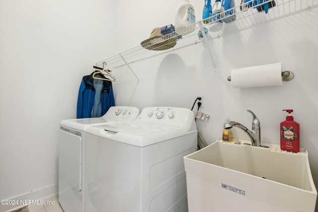 washroom featuring washer and clothes dryer, laundry area, baseboards, and a sink