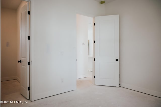 unfurnished bedroom featuring concrete floors and baseboards