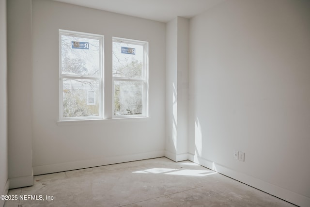 spare room with concrete flooring and baseboards