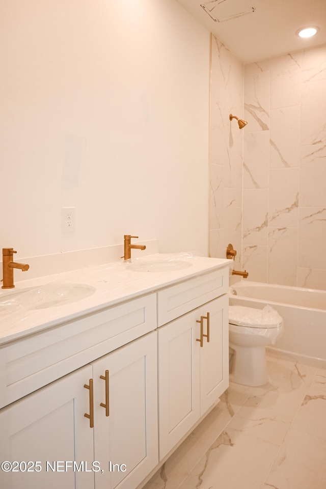 full bath with marble finish floor, double vanity, a sink, and toilet