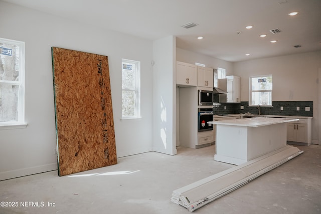 kitchen with stainless steel appliances, visible vents, a sink, and a kitchen island