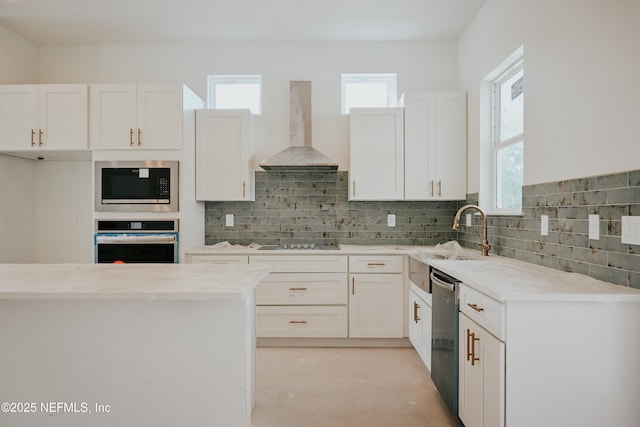 kitchen with stainless steel appliances, backsplash, white cabinetry, a sink, and exhaust hood