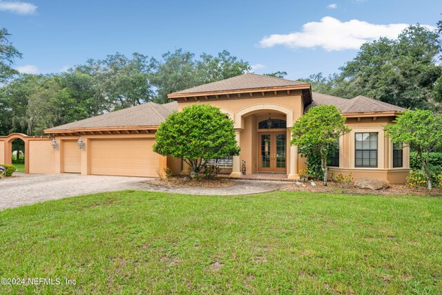 mediterranean / spanish-style home featuring a garage, a front yard, and french doors