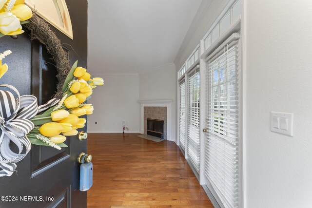 living room featuring crown molding, a tiled fireplace, and hardwood / wood-style floors