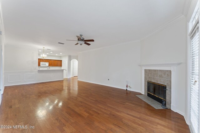 unfurnished living room with ceiling fan, hardwood / wood-style flooring, a fireplace, and ornamental molding