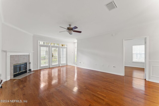 unfurnished living room with plenty of natural light, hardwood / wood-style floors, ceiling fan, and a tile fireplace